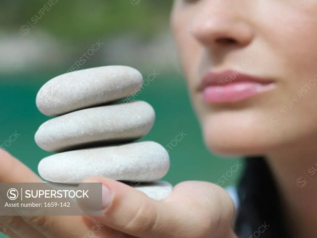 Close-up of a young woman holding a stack of stones on her palm