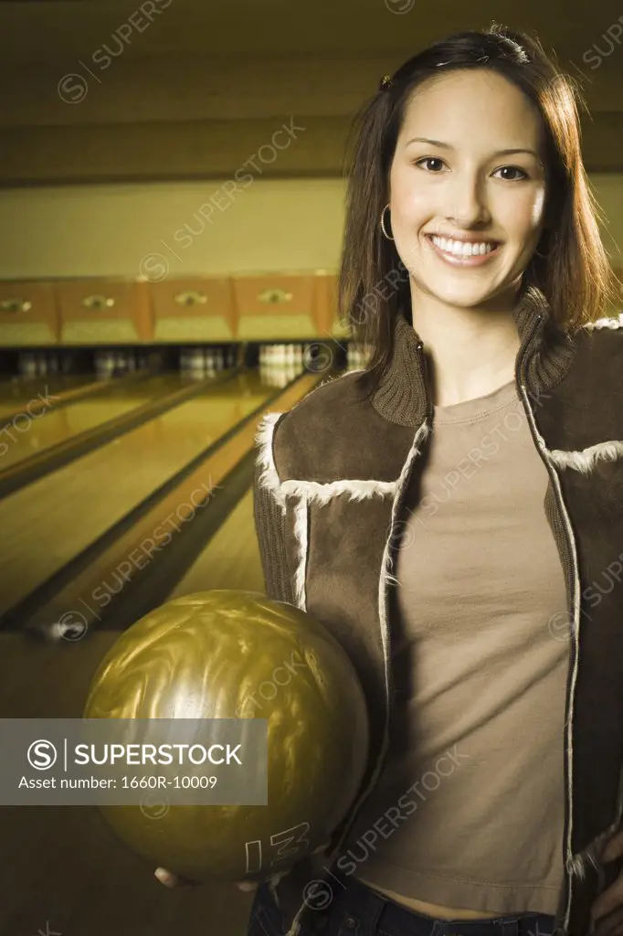 Portrait of a teenage girl holding a bowling ball and smiling