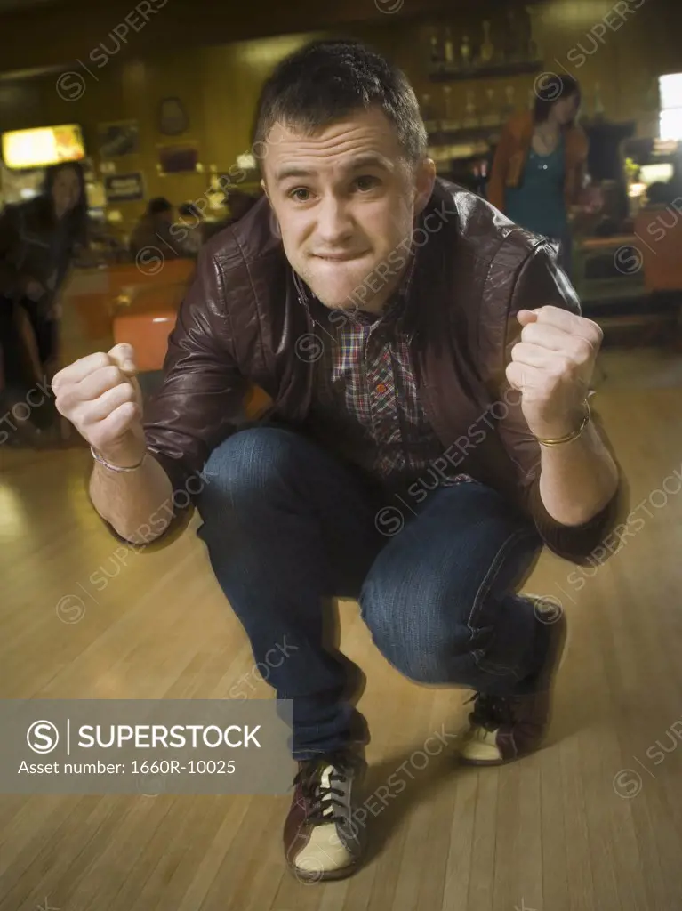 Young man cheering in excitement at a bowling alley