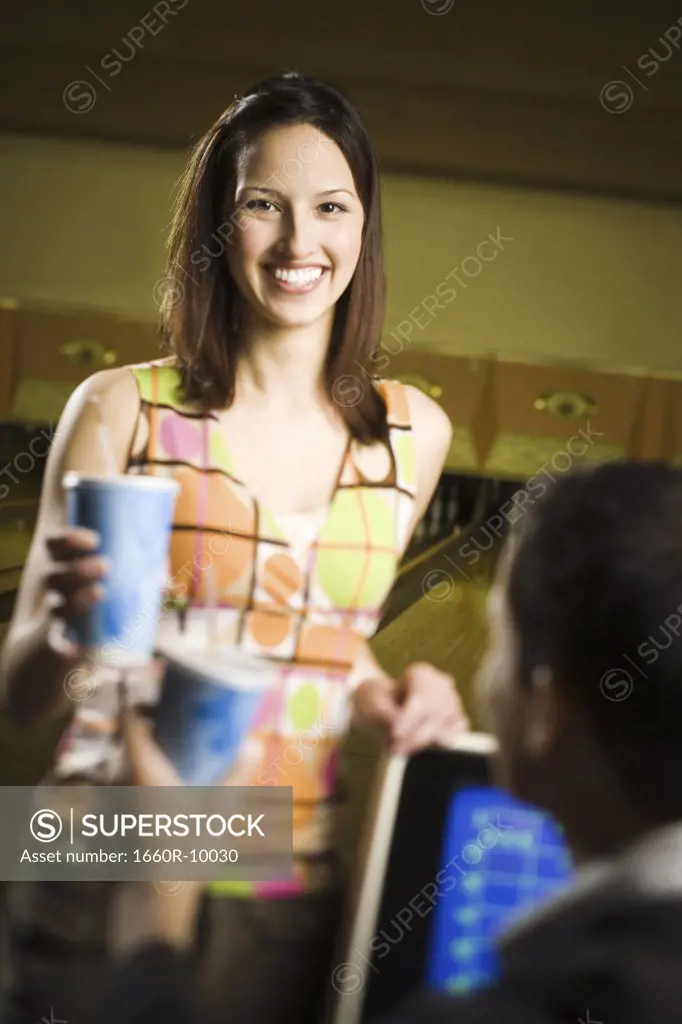 Portrait of a teenage girl holding a disposable glass of cola with a young man