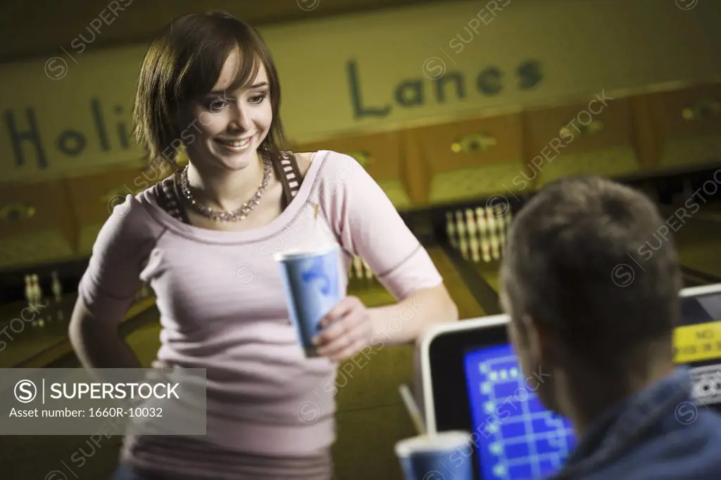 Teenage girl holding a disposable glass of cola and looking at a young man