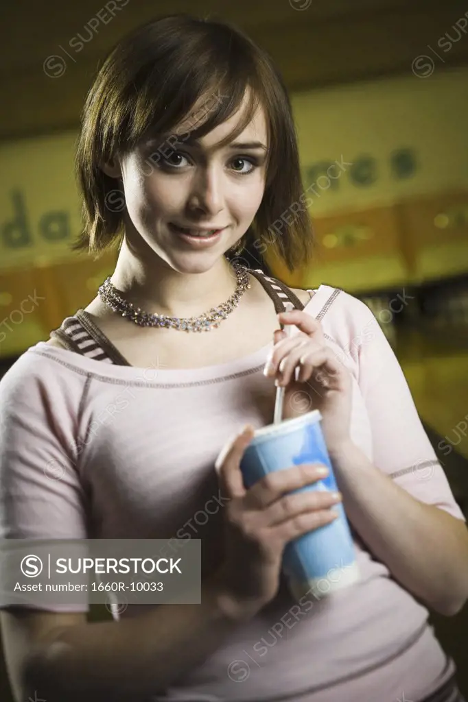 Portrait of a teenage girl holding a disposable glass of cola and smiling