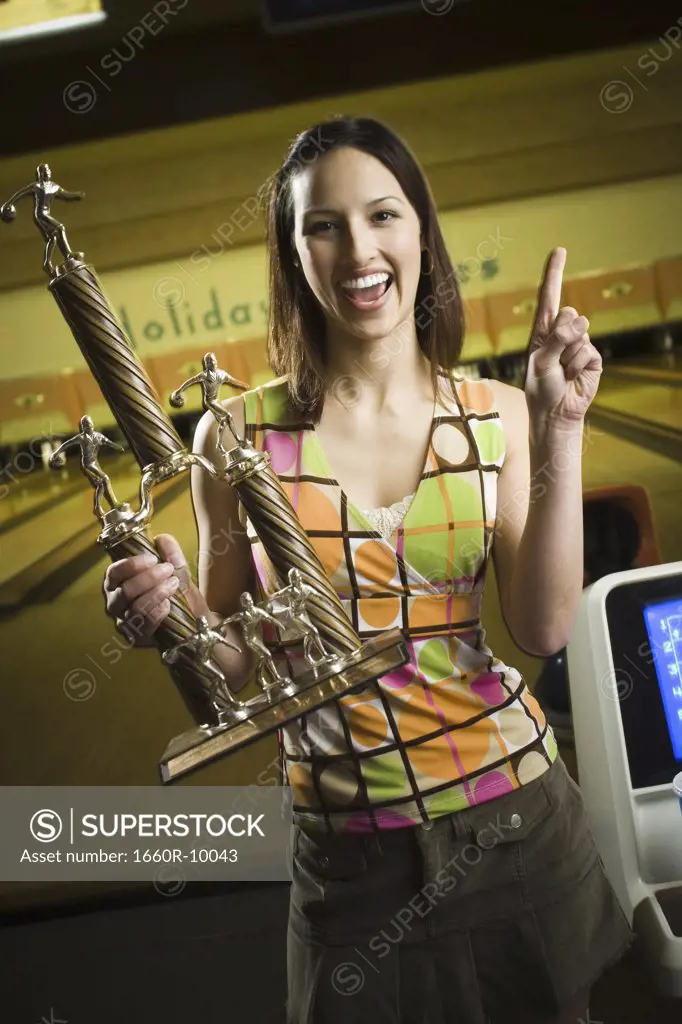 Portrait of a teenage girl holding a bowling trophy and laughing
