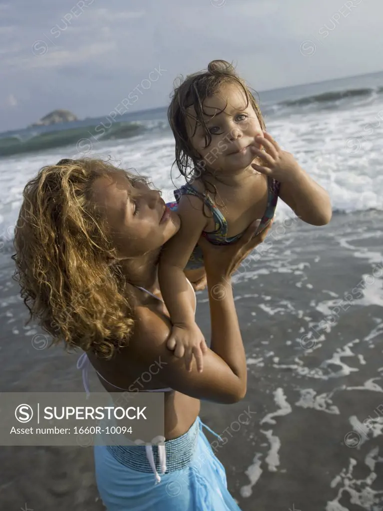 Profile of a adult woman picking up her daughter on the beach