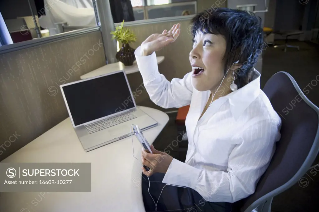 High angle view of a businesswoman listening to an MP3 player
