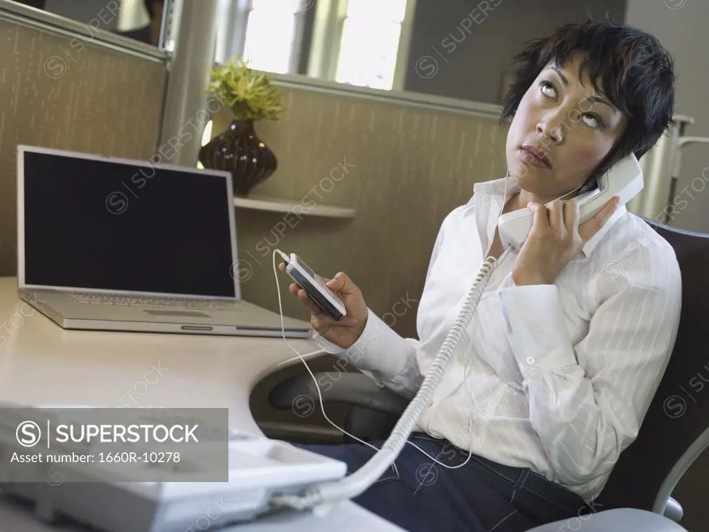 Close-up of a businesswoman with an MP3 player in her hand talking on the telephone