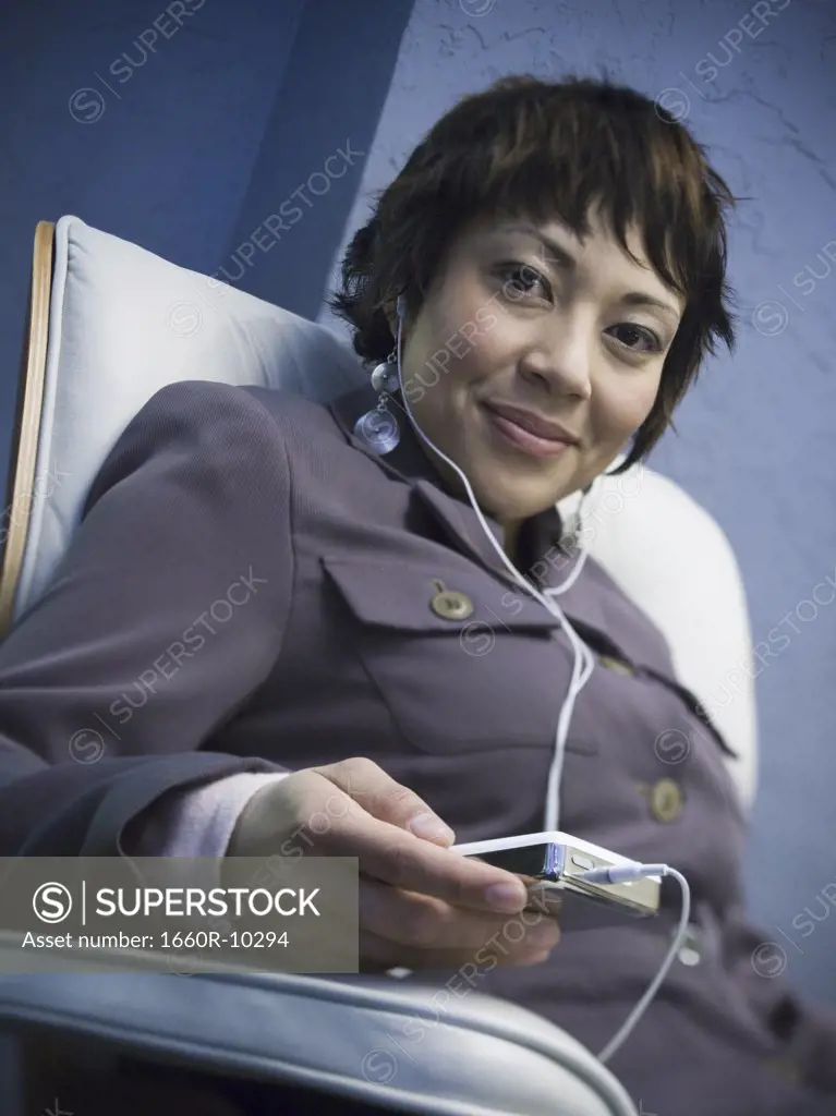 Portrait of a businesswoman listening to an MP3 player with headphones