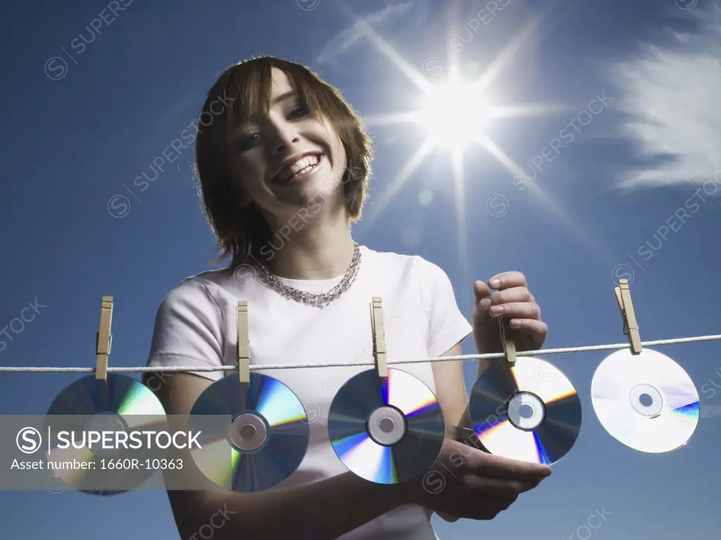 Portrait of a teenage girl drying CDs on a clothesline