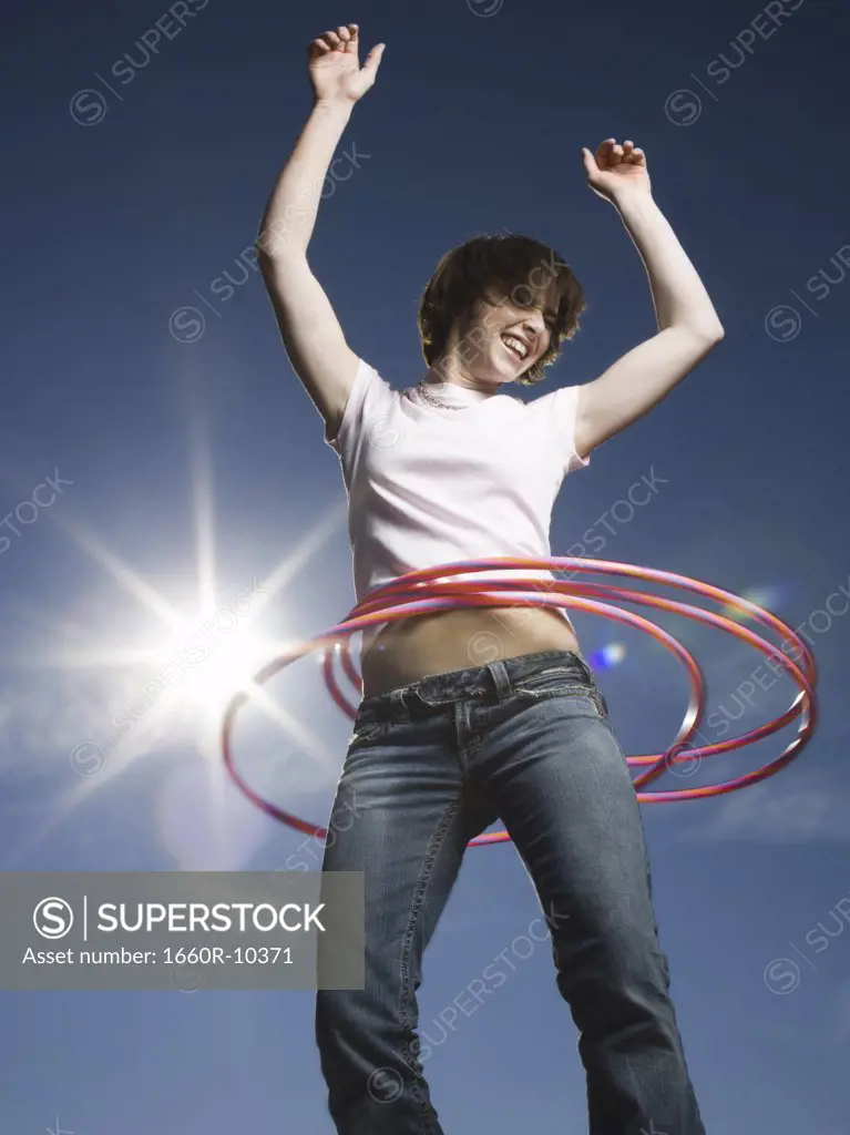 Low angle view of a teenage girl spinning hula hoops around her waist