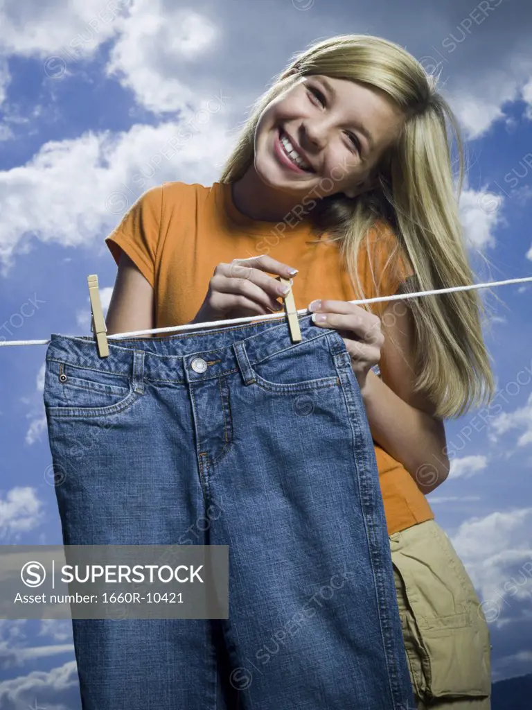 Portrait of a girl drying a pair of jeans on a clothesline