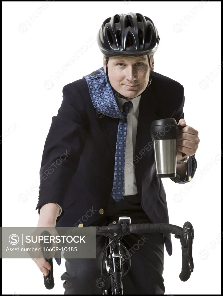 Close-up of a businessman cycling with a mug in his hand