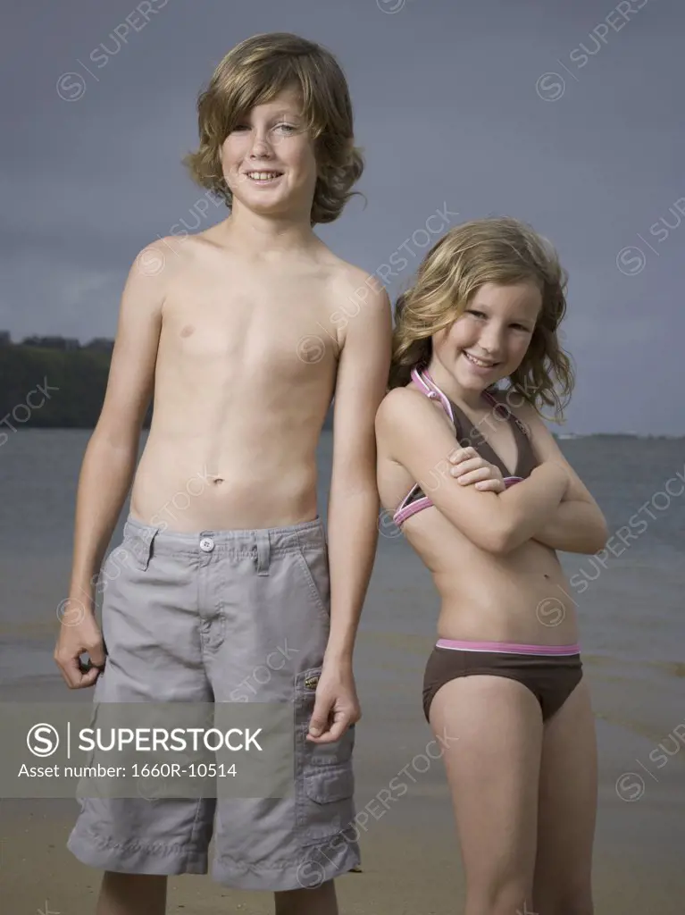 Portrait of a boy and his sister standing on the beach