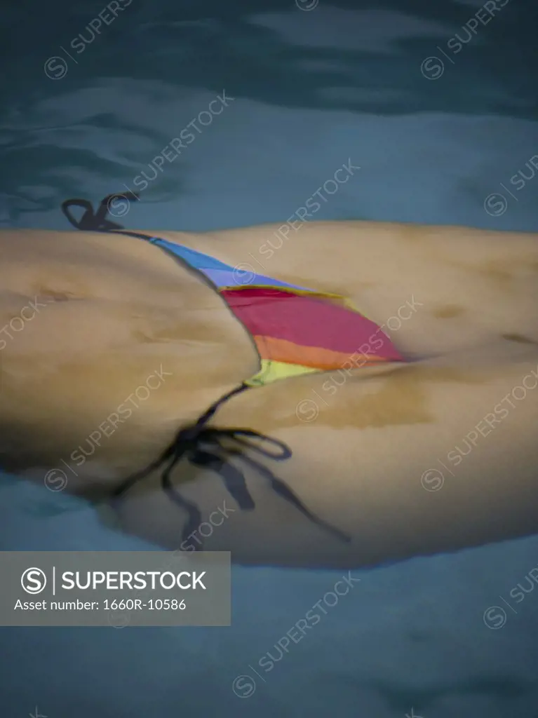 Mid section view of an adult woman swimming in a swimming pool
