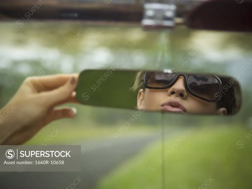 Reflection of a young woman in a rear view mirror