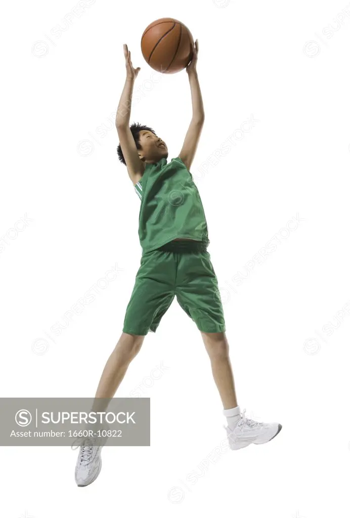 Low angle view of a boy jumping and throwing a basketball