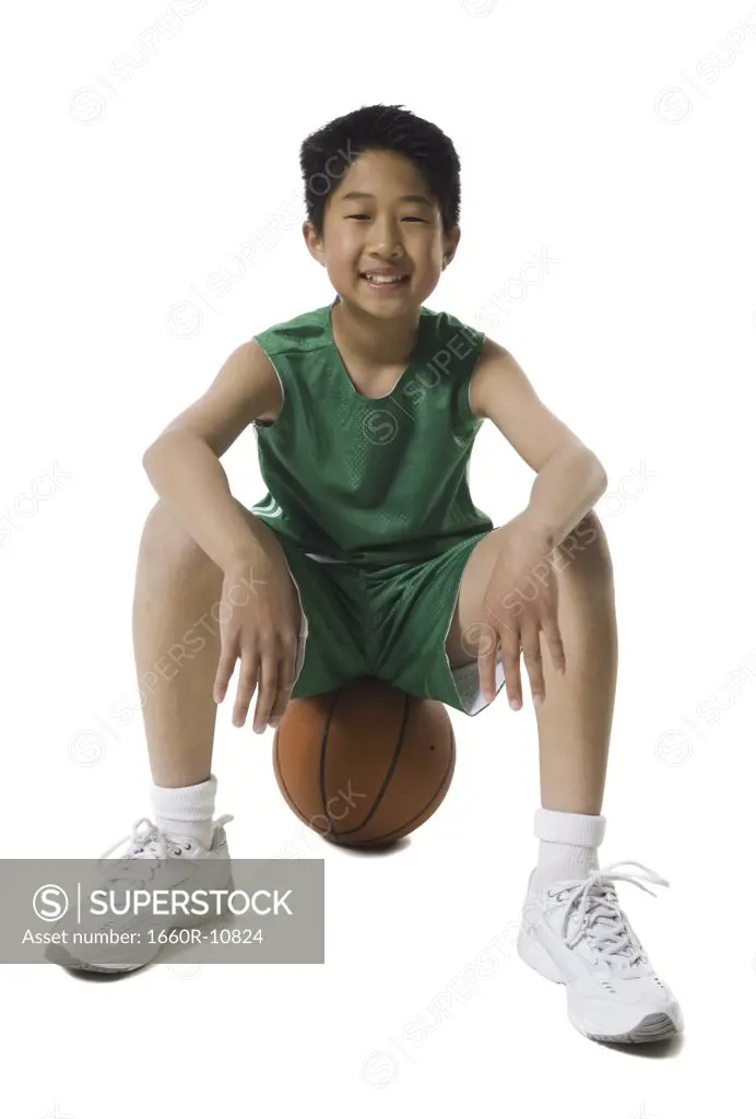 Portrait of a boy sitting on a basketball and smiling