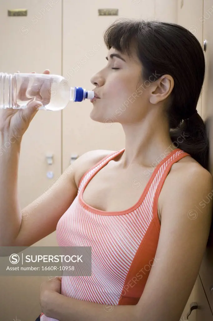 Profile of a young woman drinking water from a water bottle