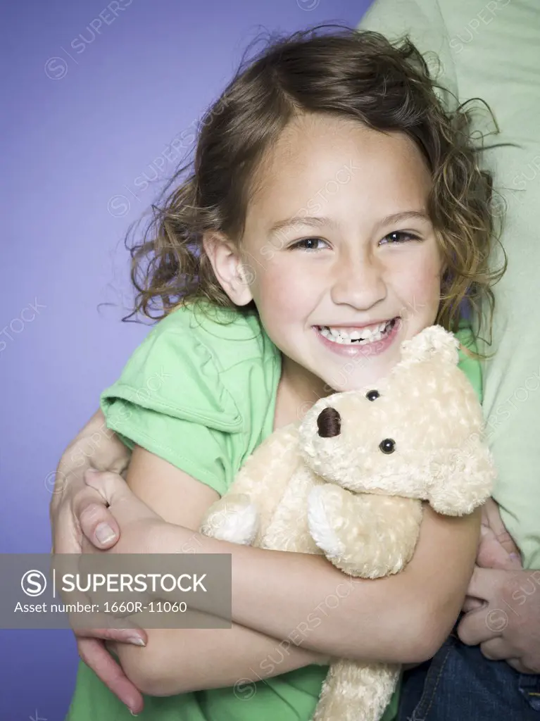 Close-up of a girl hugging a teddy bear with her mother
