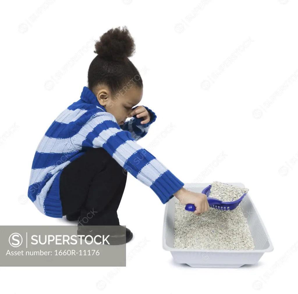 Profile of a girl cleaning a litter box with a scoop