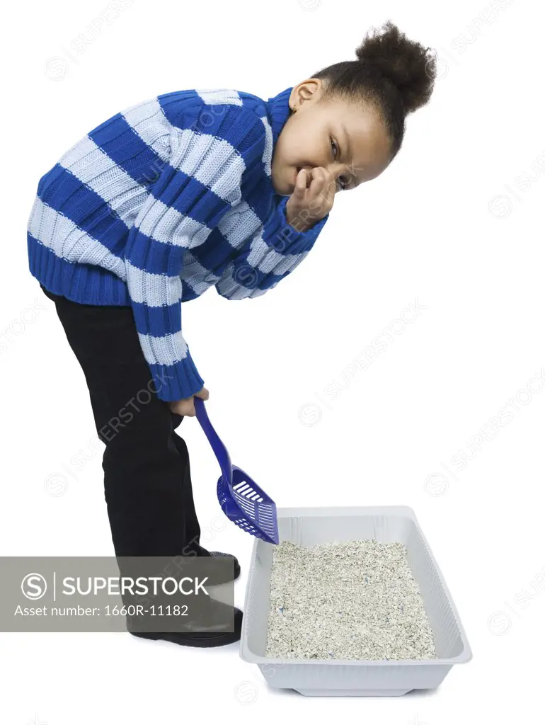 Portrait of a girl cleaning a litter box with a sand pail