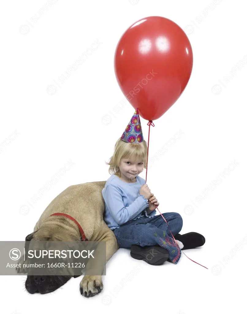 Portrait of a girl sitting beside a dog holding a balloon