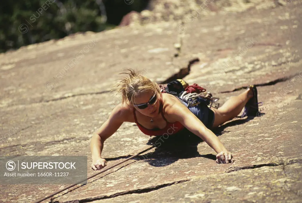 High angle view of a young woman climbing on a rock