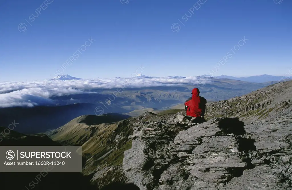 Rear view of a person sitting on a mountain