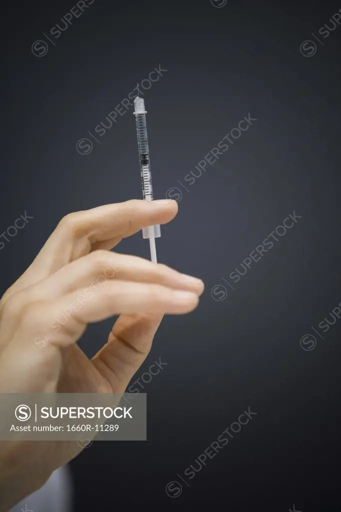 Close-up of a person's hand holding a botox syringe