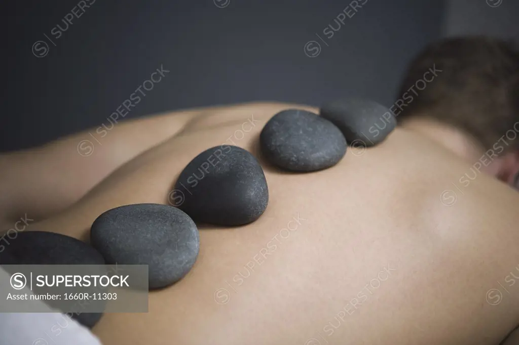 Rear view of a man getting a hot stone massage