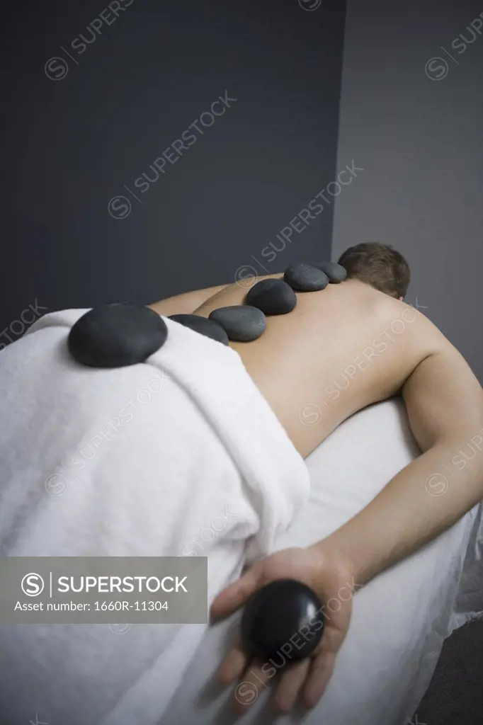 Rear view of a man getting a hot stone massage