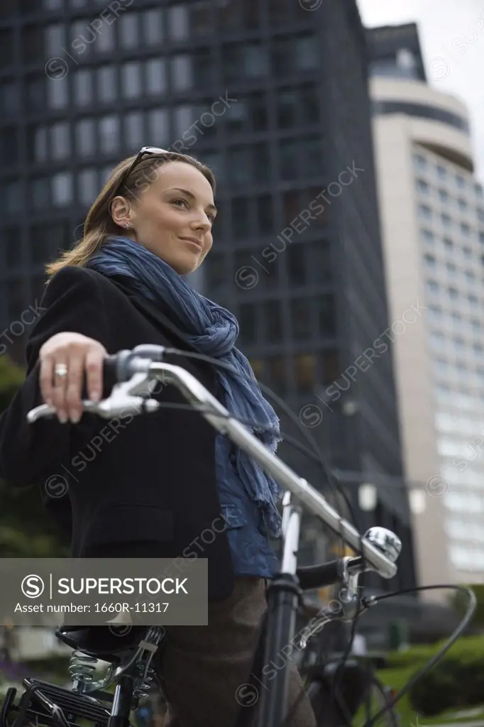 Low angle view of a young woman standing with a bicycle