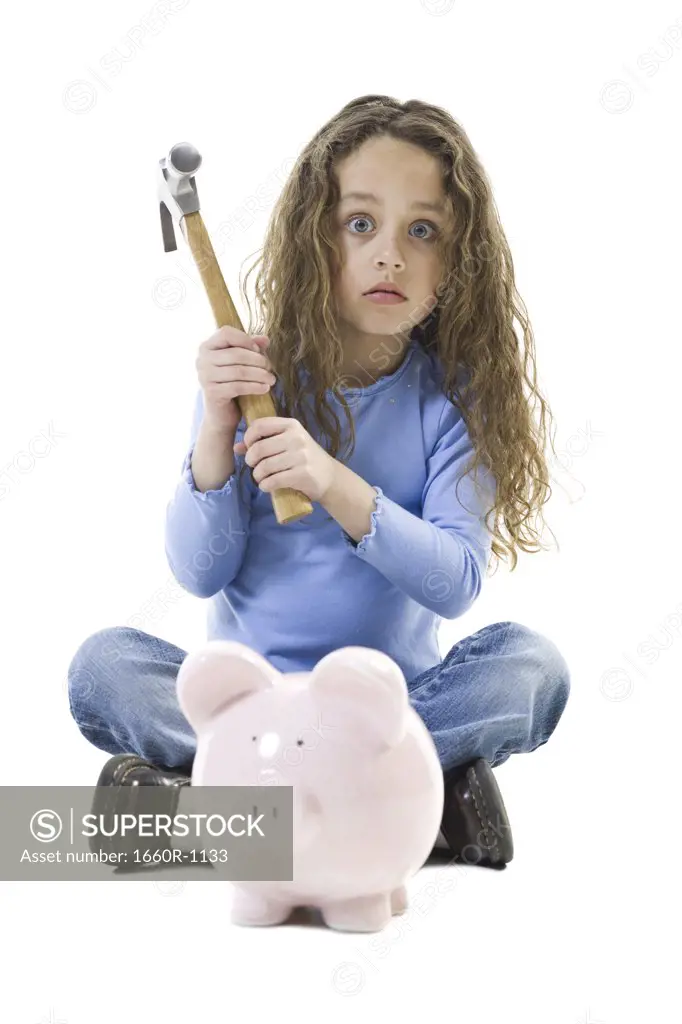 Portrait of a girl holding a hammer over a piggy bank