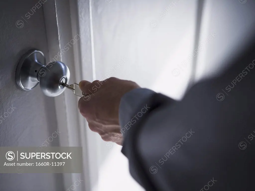 Close-up of a person's hand opening a door lock with a key