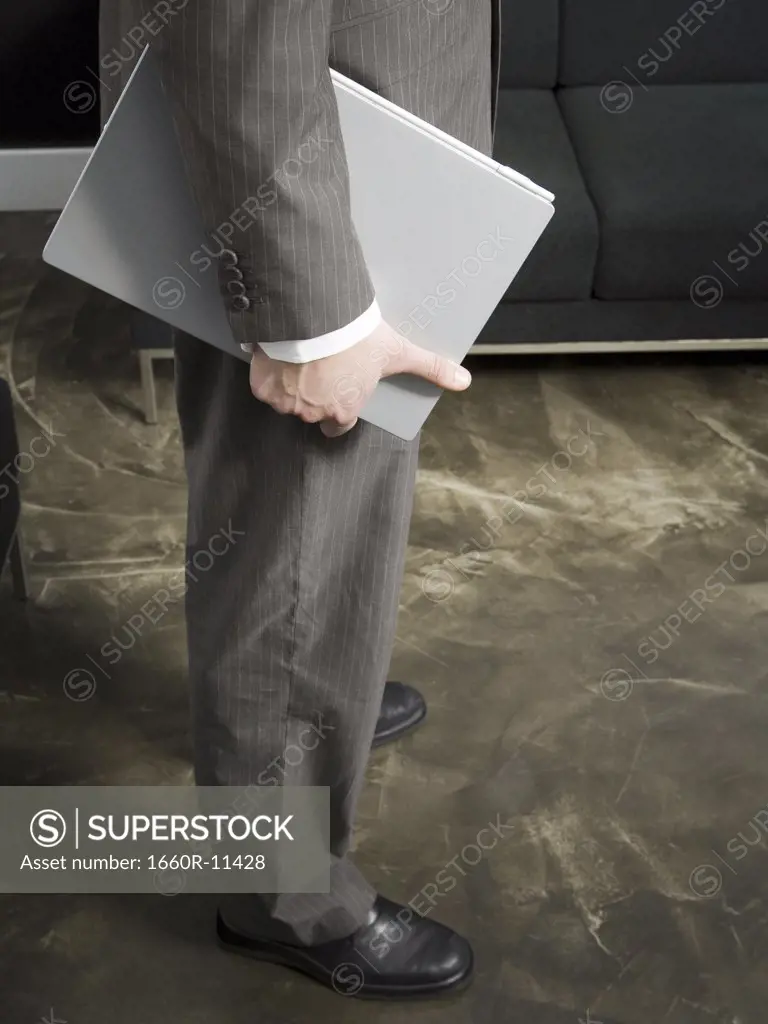 Low section view of a businessman holding a folder