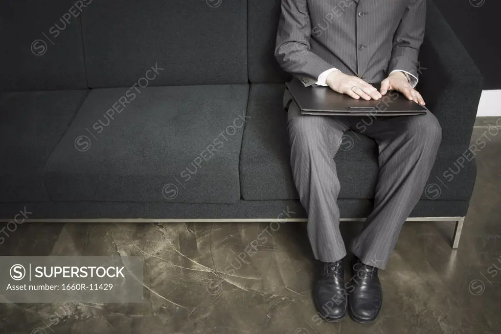 Low section view of a businessman sitting on a couch