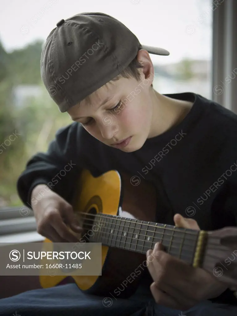Close-up of a teenage boy playing a guitar