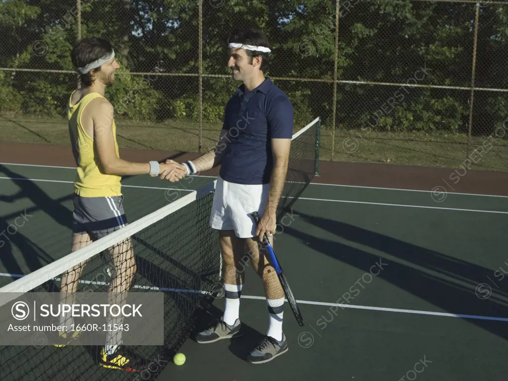 Two young men shaking hands in a tennis court