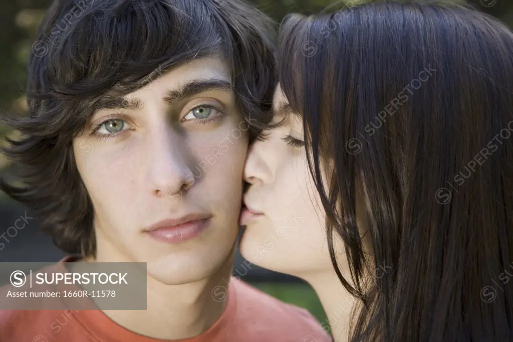 Close-up of a teenage girl kissing a teenage boy