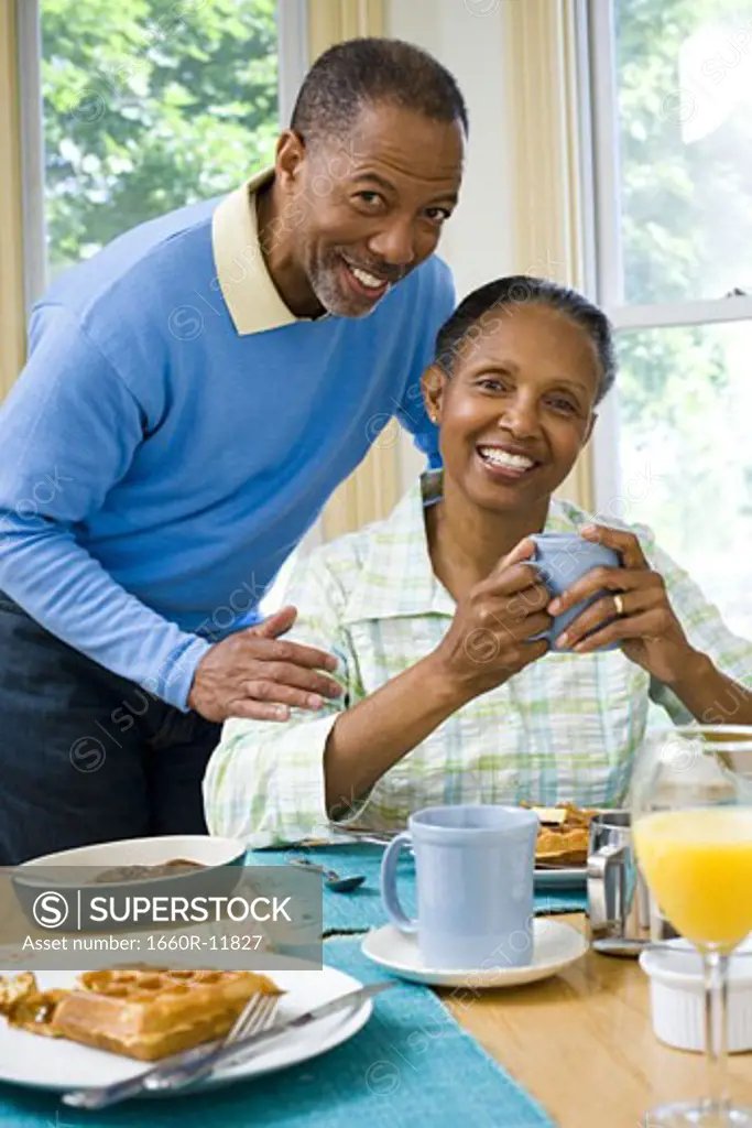 Portrait of a senior woman and a senior man smiling at the breakfast table