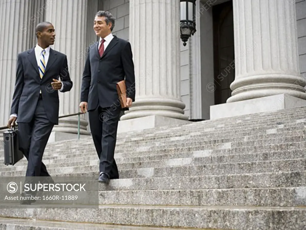 Low angle view of two male lawyers talking on the steps of a courthouse