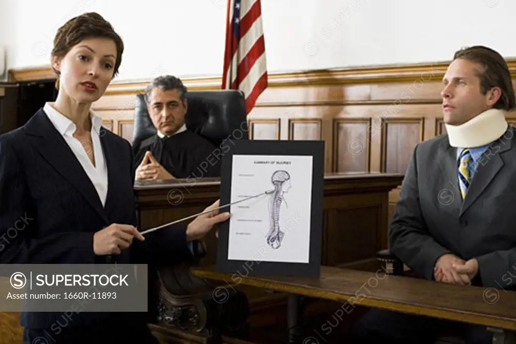 Female lawyer pointing at an exhibit in front of a judge and a victim