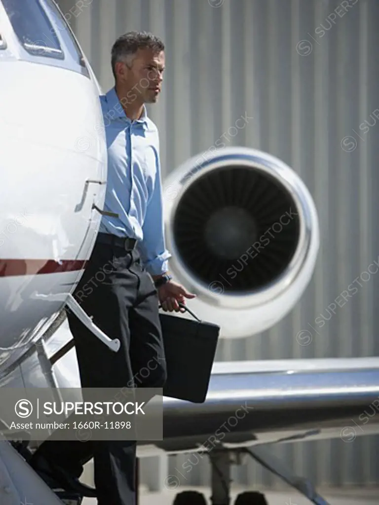 Profile of a businessman stepping down from an airplane
