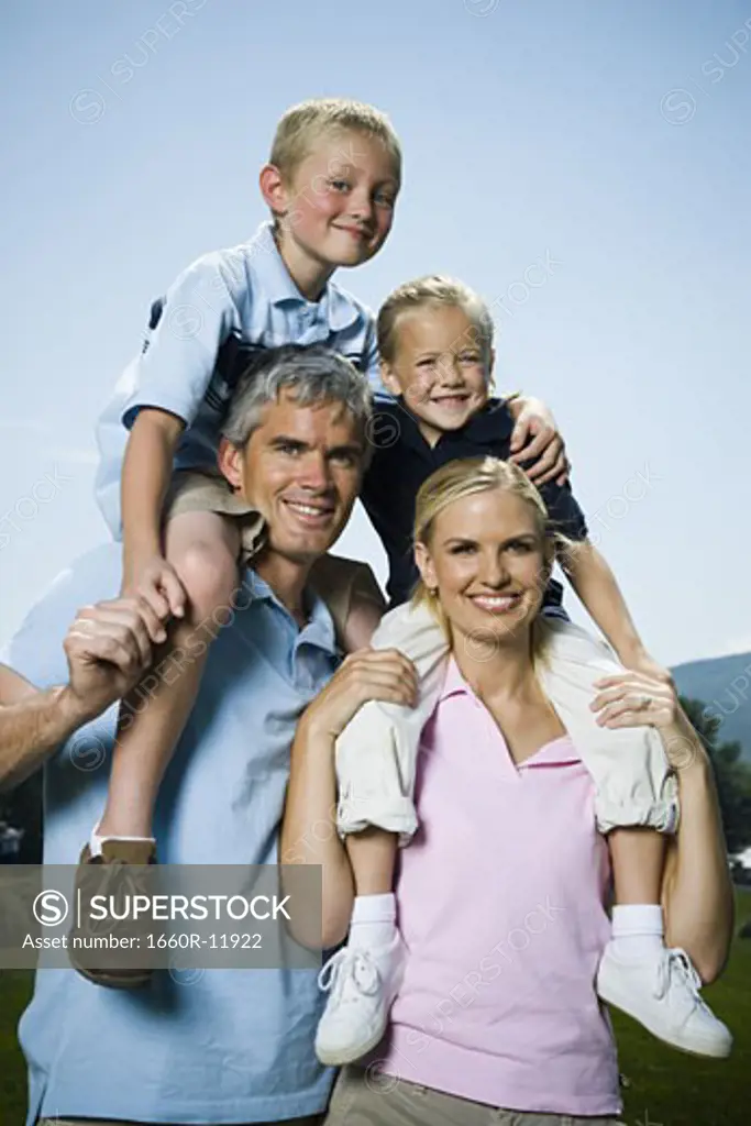 Portrait of parents carrying their two children on their shoulders