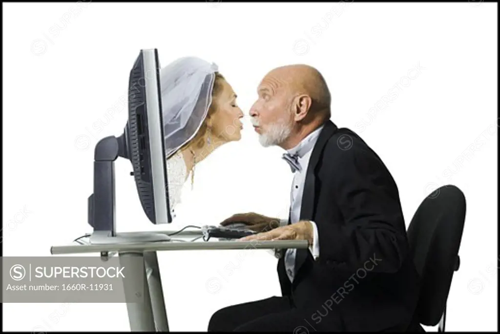Profile of a senior man kissing a senior woman emerging from a computer monitor