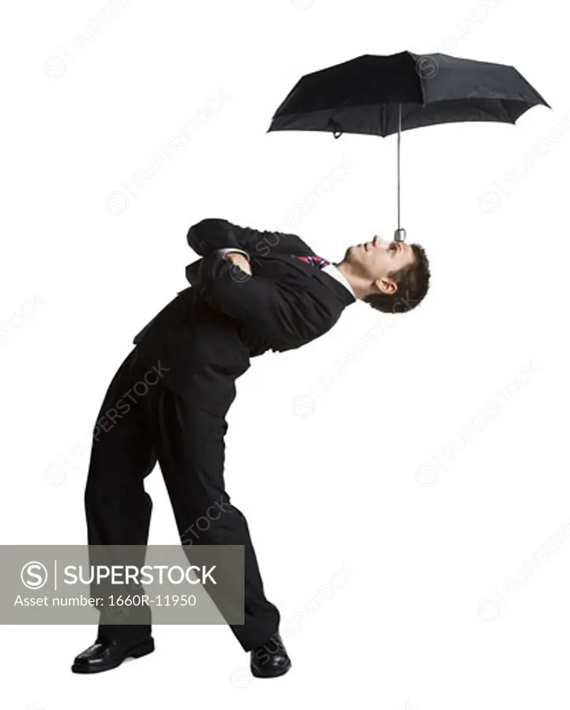Businessman balancing umbrella on his forehead