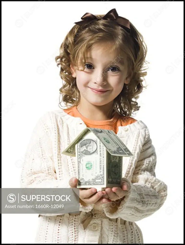 Smiling young girl in white sweater with money house