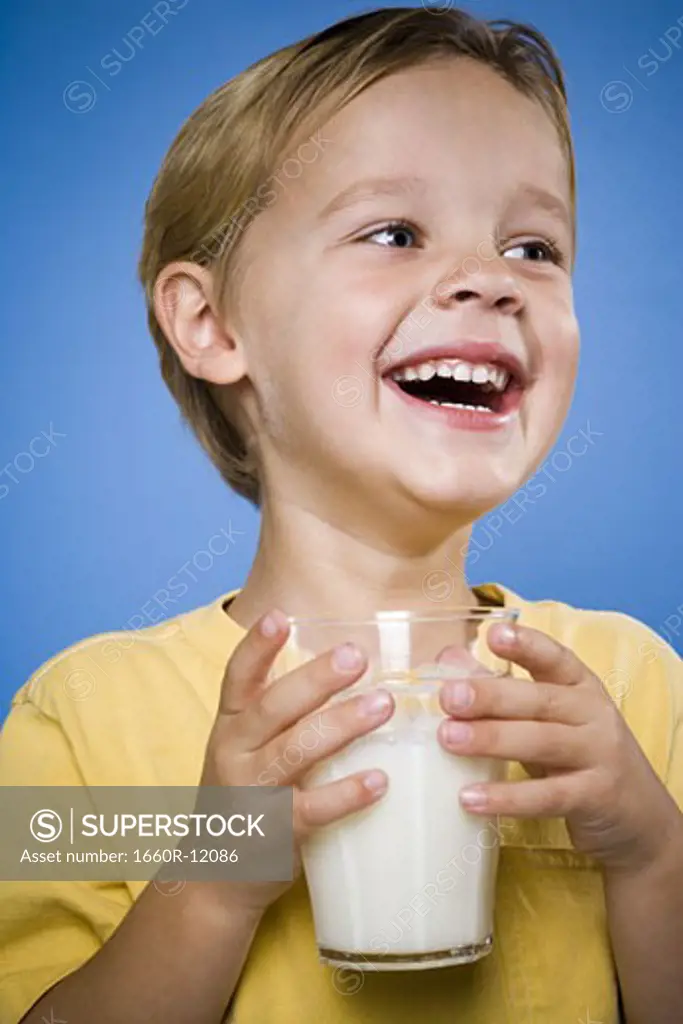 Boy with glass of milk laughing