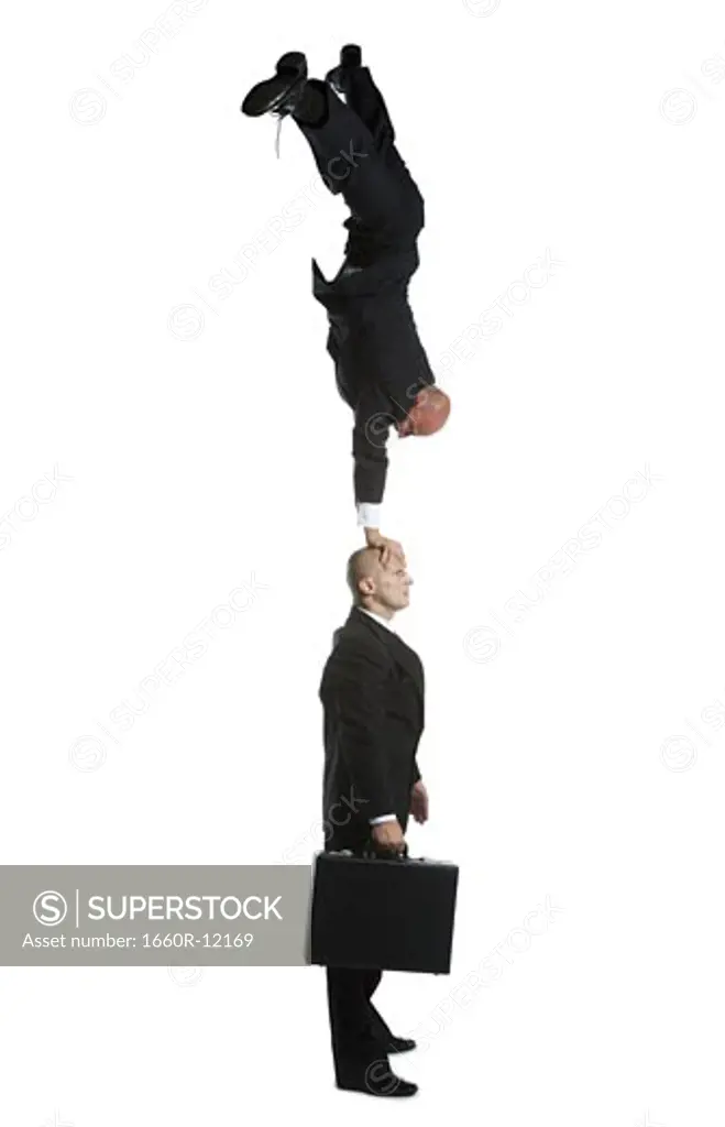 Profile of two male acrobats in business suits performing