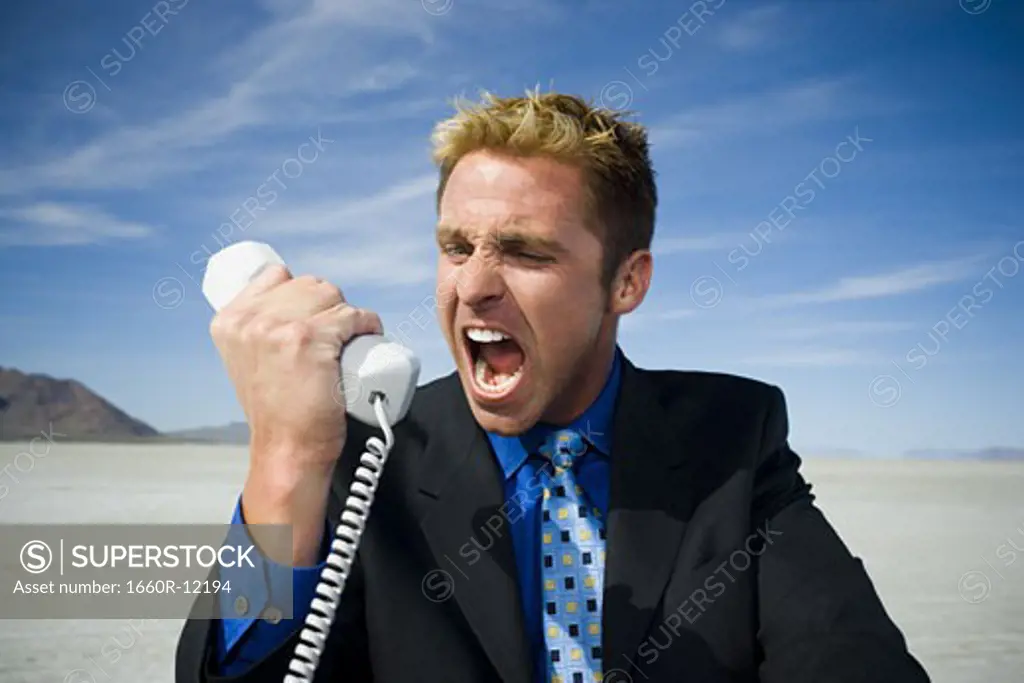 Close-up of a businessman shouting in front of a telephone receiver
