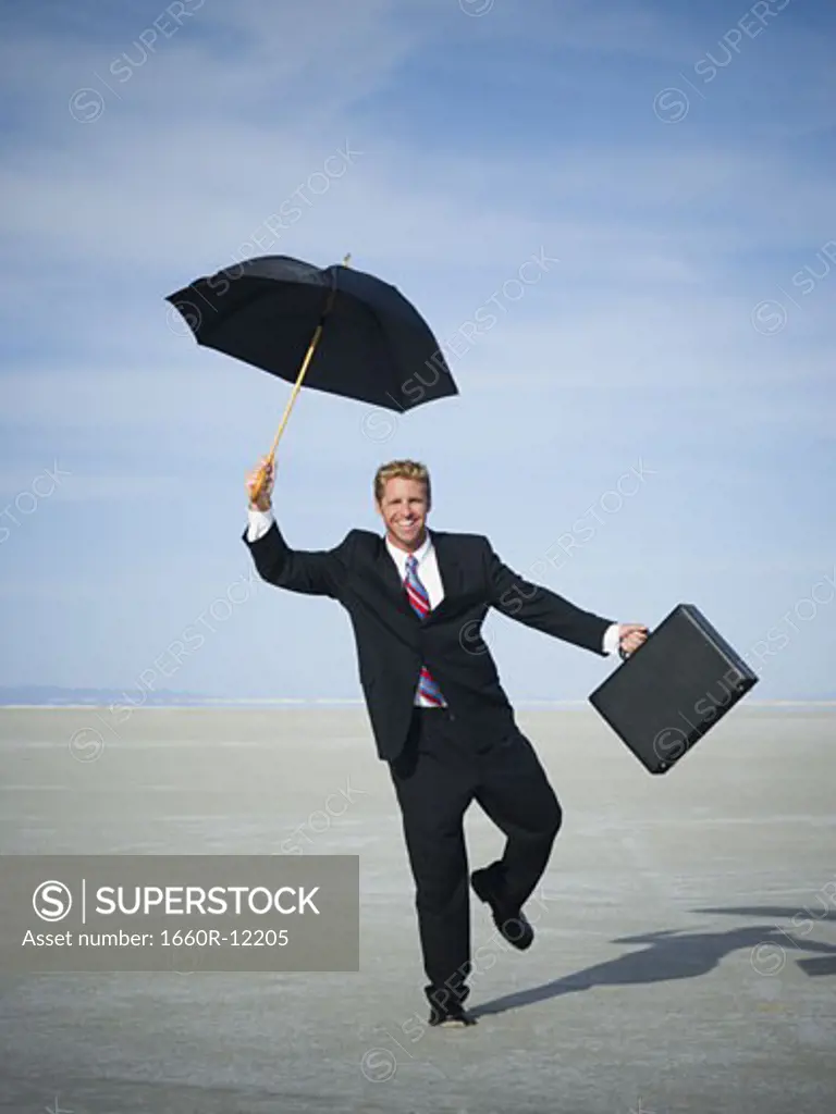 Portrait of a businessman smiling and holding an umbrella
